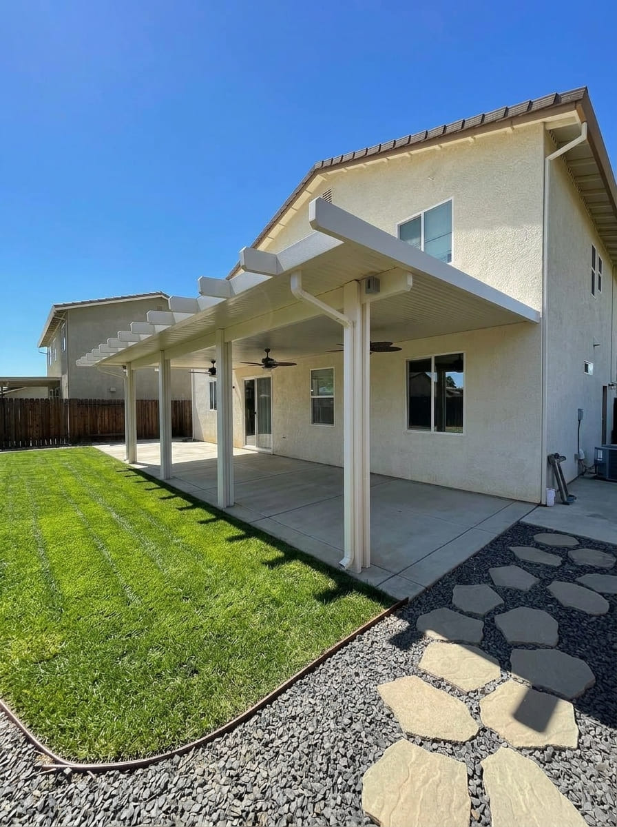 Full-length attached solid insulated aluminum patio cover with decorative corbel rafter tails and multiple integrated outdoor ceiling fans over a concrete backyard patio in Davis, CA.