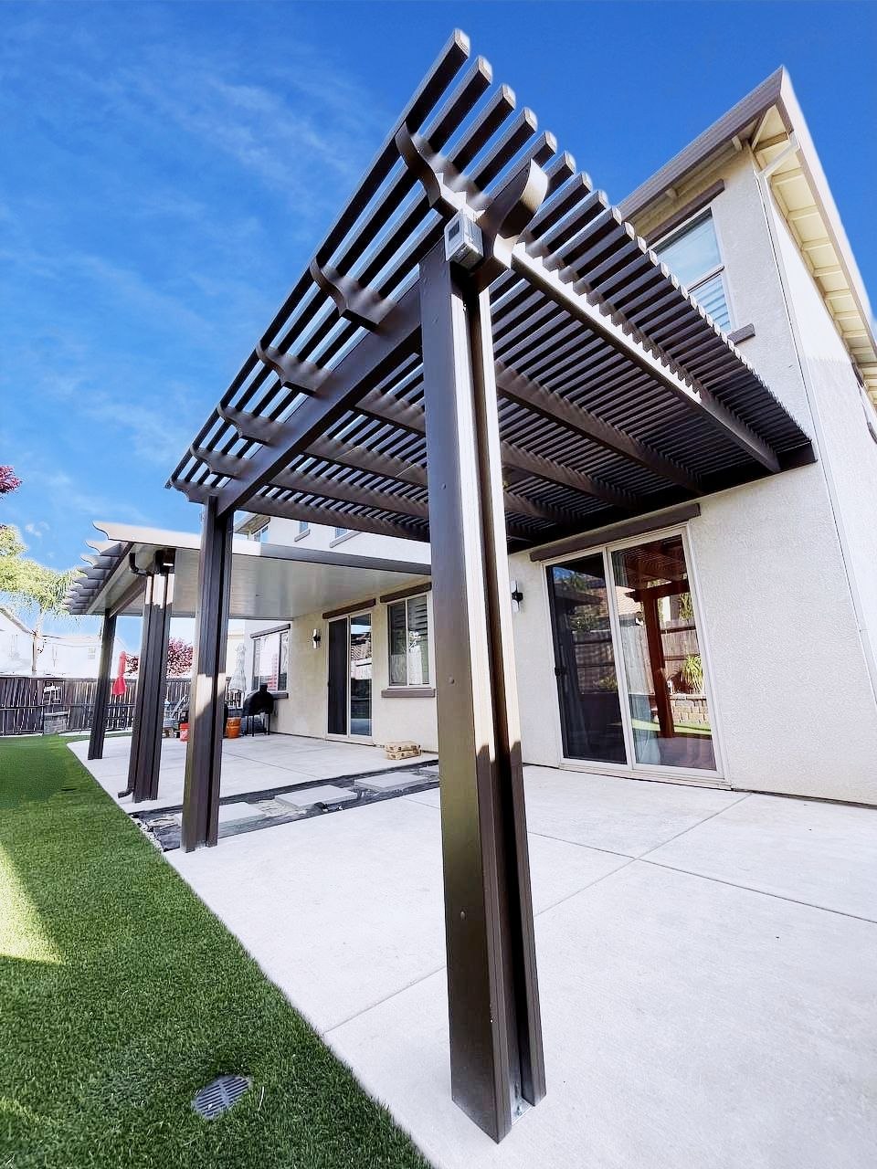 Custom attached combo patio cover featuring dark bronze lattice pergola extension connected to a solid insulated roof on a two-story home in Carmichael, CA.
