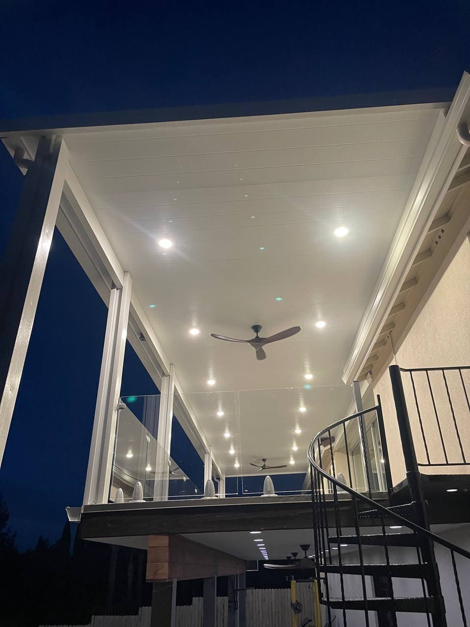 Attached solid insulated aluminum patio cover installed over a second-story balcony deck featuring recessed LED pot lights, integrated modern ceiling fans, and glass railings in El Dorado Hills, CA.