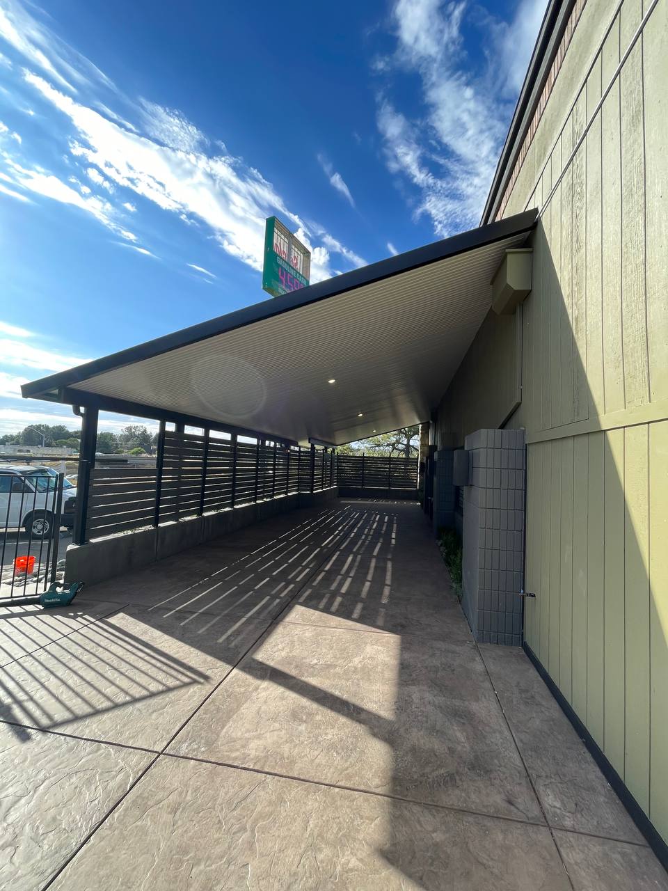 Heavy-duty attached solid insulated aluminum canopy cover with integrated recessed LED lighting and dark bronze trim over an extended stamped concrete walkway in West Sacramento, CA.